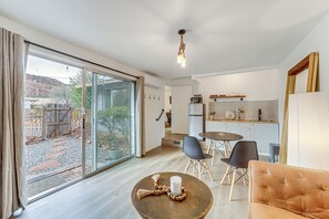 Eine moderne Küche mit Essbereich, großen Schiebeglasfenstern zum Garten und einer gemütlichen Sitzecke mit Sofa und Sesseln.