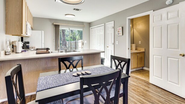 Una cocina moderna con armarios de madera, una isla central y un comedor con mesa y sillas.