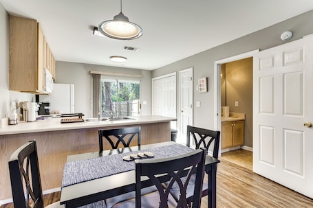 A modern kitchen with wooden cabinets, a central island, and a dining area with a table and chairs.