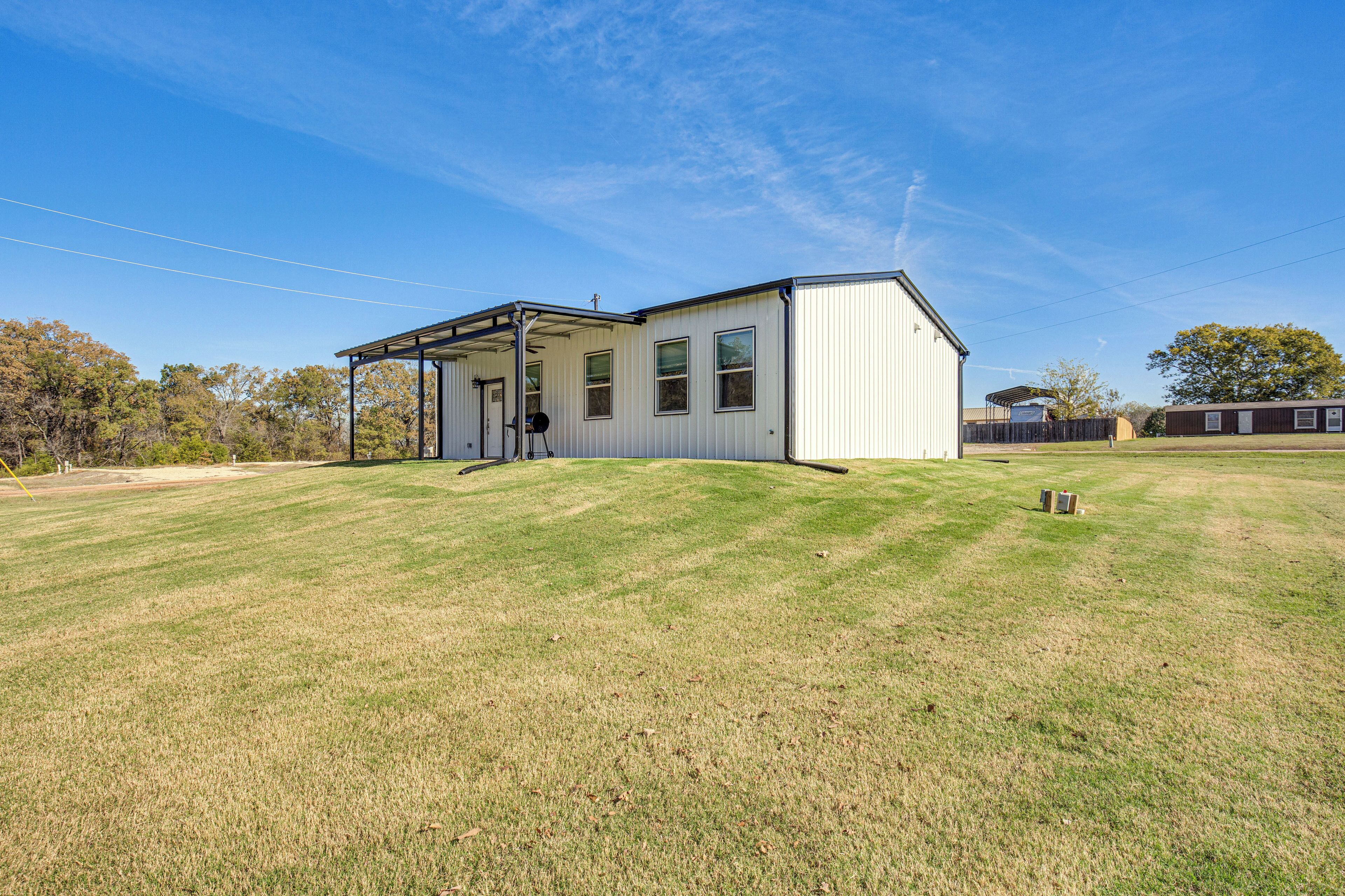A single-story building with a covered porch, a fenced yard, and a clear blue sky.