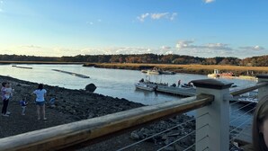 A riverside view with boats docked, a wooden pier, and a distant house. - 12 Mins from Beach - A Quiet, Immaculate space (Norwell)