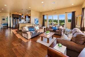 A spacious living area with a kitchen in the background, a large window with a view, and a sign that reads 'FAMILY'. - Vino On Vineyard by LUX Retreats Paso (Paso Robles)