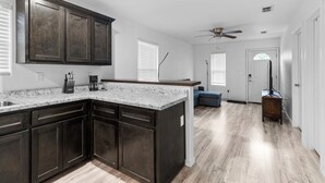 A modern kitchen with dark wood cabinets, a granite countertop, and a built-in island. - Brand New 3 bed house in central San Benito with AC, WiFi, and digital features (San Benito)