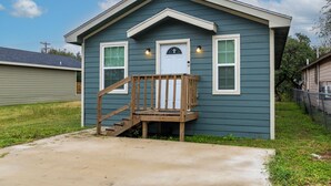 A small, single-story house with a front porch and a staircase leading to the door. - Brand New 3 bed house in central San Benito with AC, WiFi, and digital features (San Benito)