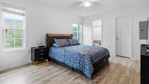 A bedroom with a bed, a nightstand, a dresser, a ceiling fan, and a door. - Brand New 3 bed house in central San Benito with AC, WiFi, and digital features (San Benito)