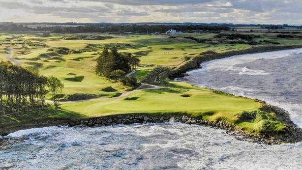 A coastal golf course with a stone wall, a path, and a building in the distance. - Charming 2-bedroom cottage in Kingsbarns  (Kingsbarns)