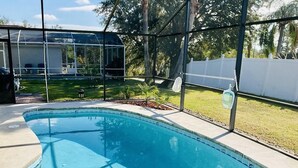 Une piscine à l’eau d’un bleu cristallin, entourée d’une structure en verre et d’une clôture blanche.
