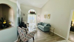 Un salon avec un fauteuil à motifs, un canapé et une petite table ronde.
