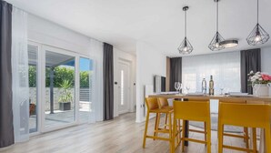 A modern dining area with a wooden table, yellow chairs, and pendant lighting. - Apartment BARBARA with private pool (Malinska)