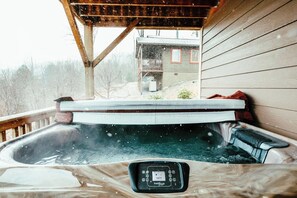 Ein Whirlpool mit Bedienfeld, einer Holzterrasse und Blick auf ein Haus im Hintergrund.