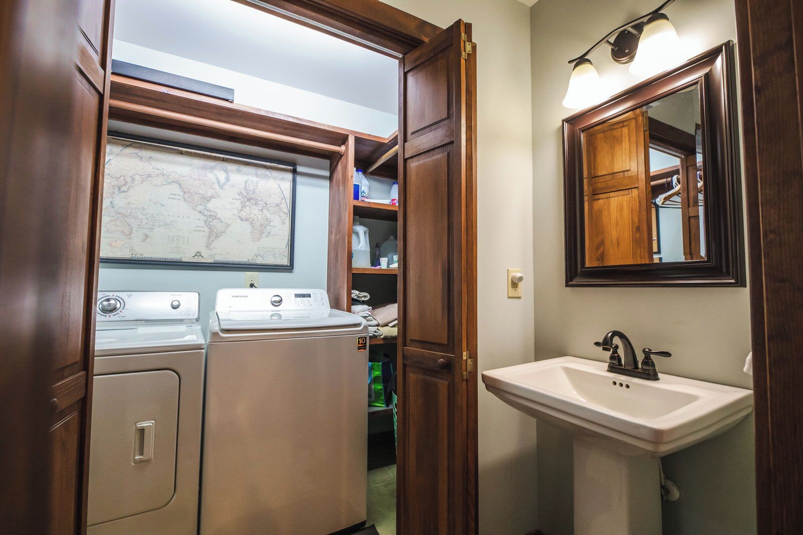 A compact laundry area with a washing machine and dryer, a wooden cabinet, and a sink with a mirror above it.