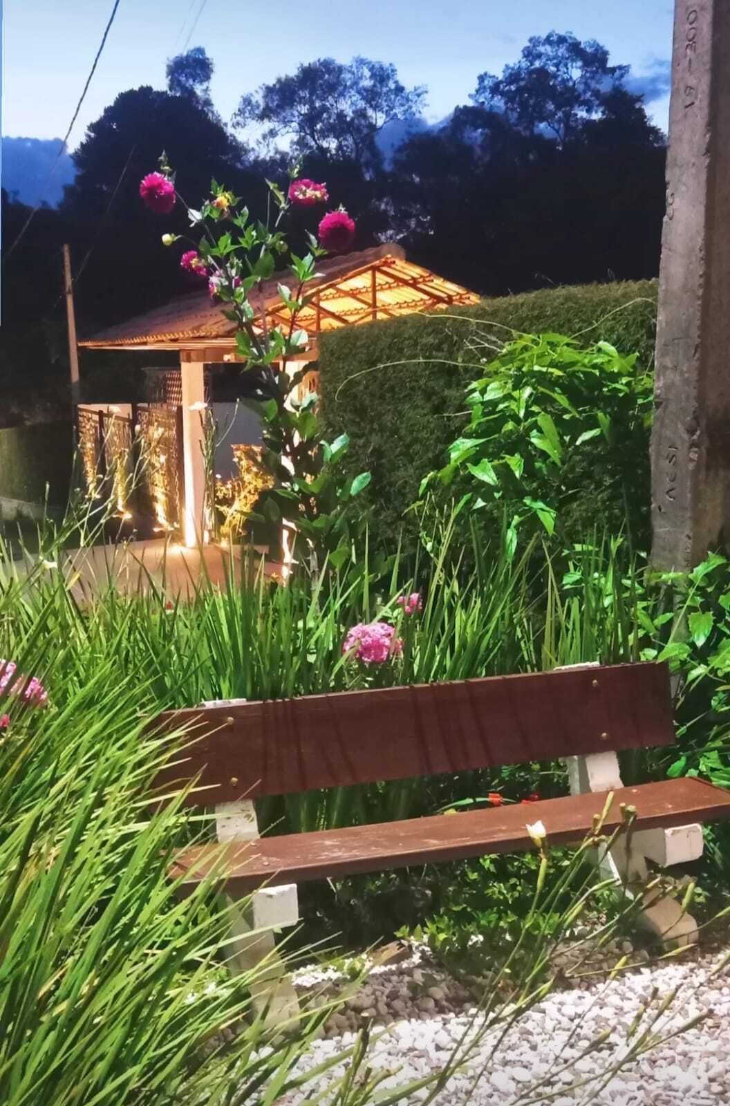 Un banco de madera en un jardín, con un quiosco de fondo.