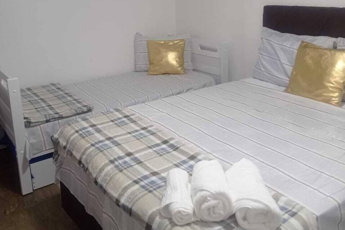 A single-bed room with a white air conditioner, a wooden headboard, and a bedside table.
