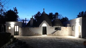 A rustic building with a stone facade, a central arched entrance, and multiple conical roofs. - Trullo near Ostuni quiet with fenced heated pool with Starlink wifi (Latiano)