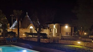 A nighttime view of a pool area with a stone building in the background. - Trullo near Ostuni quiet with fenced heated pool with Starlink wifi (Latiano)