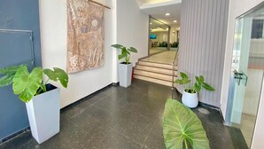 Un hall d’entrée moderne avec un escalier, des plantes en pot et une grande œuvre d’art abstraite accrochée au mur.