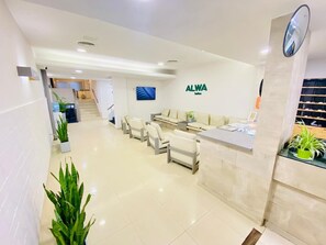 A reception area with a reception desk, seating area, and a staircase leading to other floors. - ALWA Suites (Resistencia)