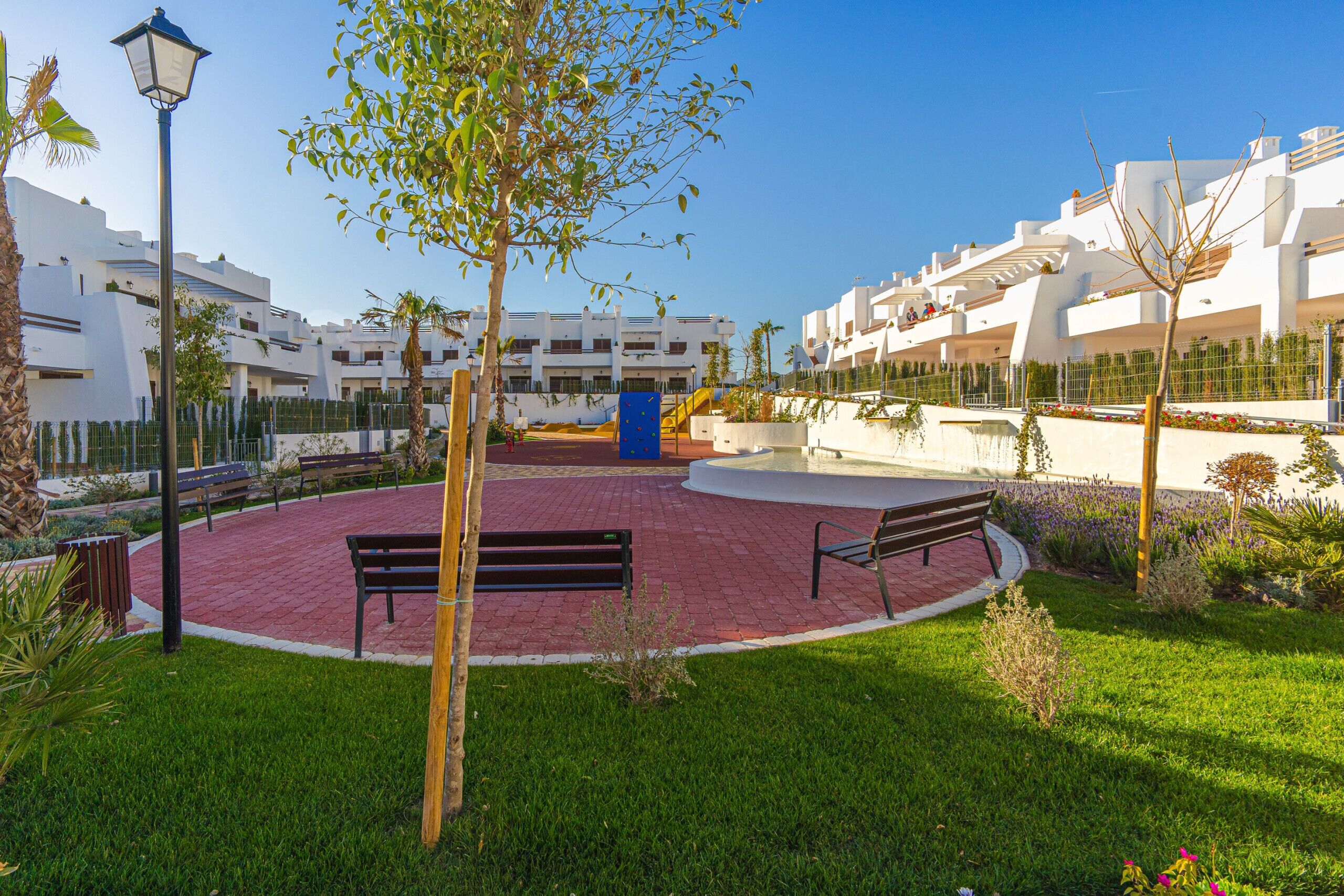 A courtyard with benches, a lamp post, and a playground.