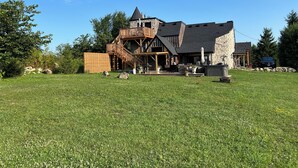 A large stone building with a wooden deck and a stone chimney. - The Castle - 4-bedroom house with AC, WiFi in Grey County (Feversham)