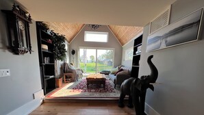 A spacious living room with a high ceiling, wooden flooring, a large window, and a view of the outdoors. - The Castle - 4-bedroom house with AC, WiFi in Grey County (Feversham)