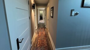 A hallway with a patterned carpet, a door with a black handle, and a wall-mounted intercom. - The Castle - 4-bedroom house with AC, WiFi in Grey County (Feversham)