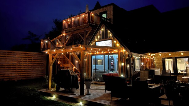 A wooden deck with outdoor seating and a staircase leading to a balcony. - The Castle - 4-bedroom house with AC, WiFi in Grey County (Feversham)