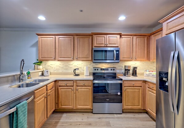 Enjoy cooking in this well-equipped kitchen with a double sink, microwave, stove, and refrigerator.