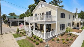 A two-story house with a balcony on the upper floor, a front porch, and a small front yard with shrubs.