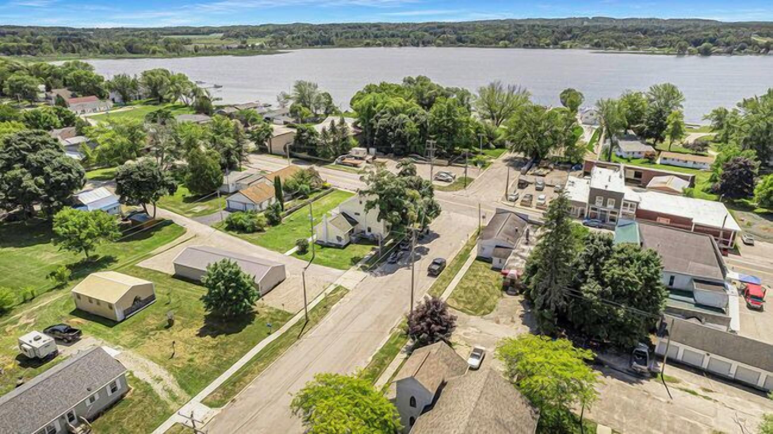 Un quartier résidentiel avec des maisons, une route et une grande étendue d’eau en arrière-plan.