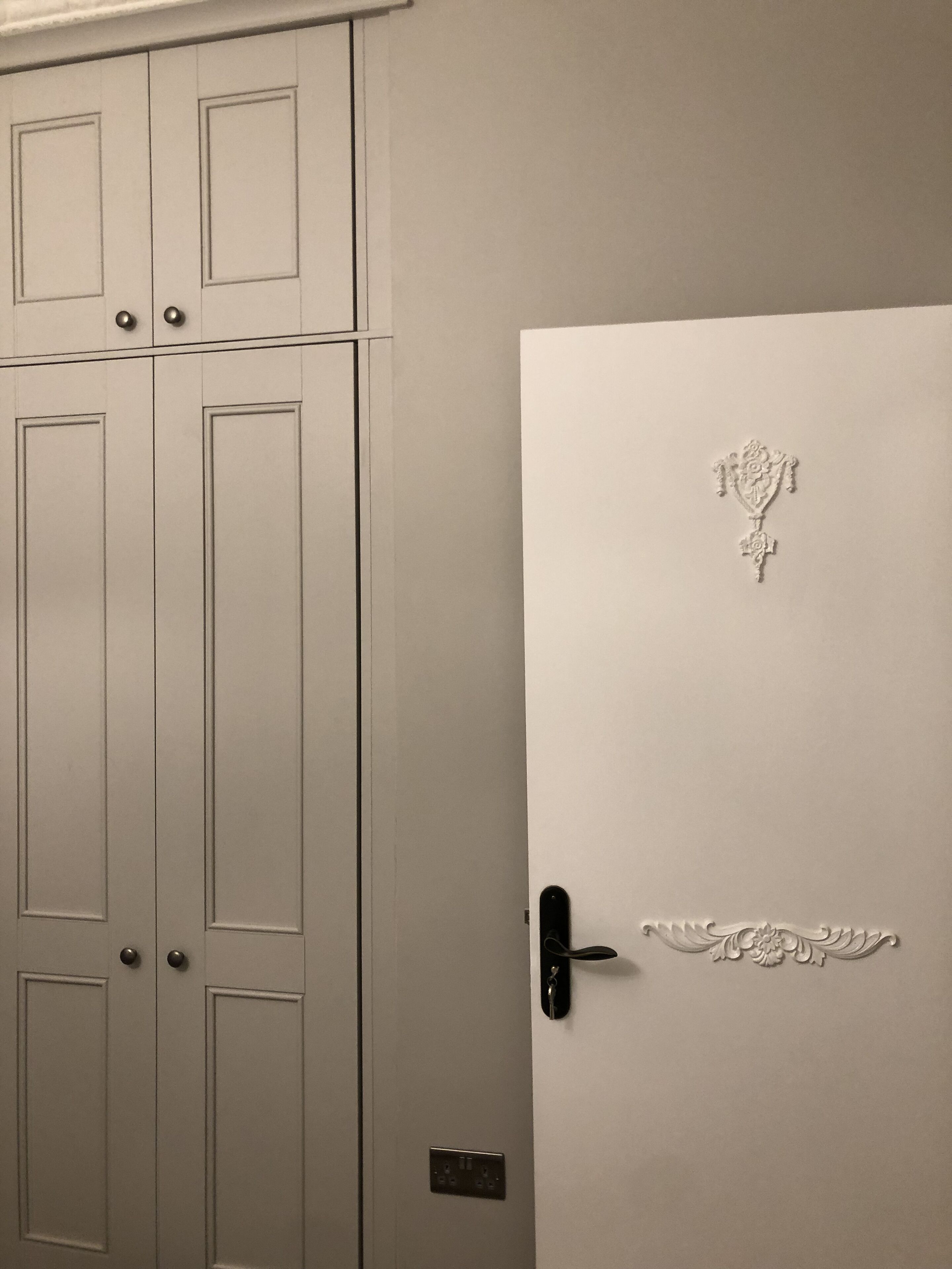 Une porte blanche ornée d’un motif décoratif et dotée d’un trou de serrure.