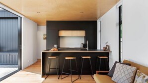 Une cuisine moderne dotée d’un îlot central, de tabourets de bar et d’un canapé avec des coussins.