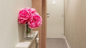 A hallway with a radiator, a door with a sign, and a vase with flowers on a shelf. - De Montescal - Cozy A/C small Studio (Paris)