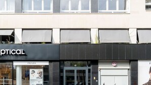 A building with a storefront labeled 'OPTICAL' and a Prada store across the street. - De Montescal - Cozy A/C small Studio (Paris)