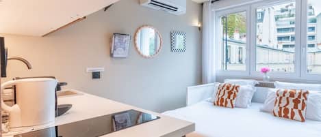 Una habitación de hotel moderna con una cama, mesita de noche y vistas a la ciudad a través de amplios ventanales.