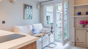 A modern living room with a sofa, a dining table, and a kitchen area. - De Montescal - Studio (Paris)