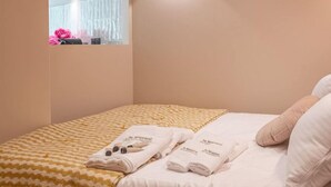 A bedroom with a bed, towels, a mirror, and a wall-mounted light fixture. - De Montescal - Hot tub & A/C Apartment (Paris)