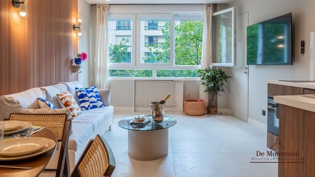 A modern living room with a sofa, coffee table, and dining area. - De Montescal - Hot tub & A/C Apartment (Paris)