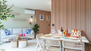 A modern living room with a dining area, featuring a sofa, coffee table, and a dining table set for two. - De Montescal - Hot Tub A/C small appartment (Paris)