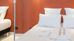 A hotel room with a bed, white pillows, and a nightstand with folded towels. - De Montescal - Hot Tub A/C Wonder (Paris)