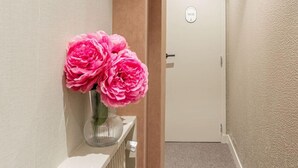 A hallway with a radiator, a door with a sign, and a vase with flowers on a shelf. - De Montescal - Hot Tub A/C Wonder (Paris)