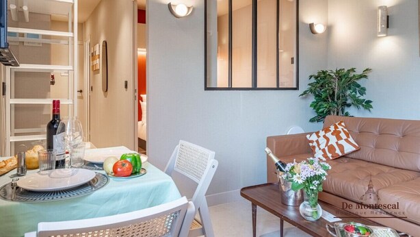 A modern living room with a dining area, a sofa, and a table set for a meal.