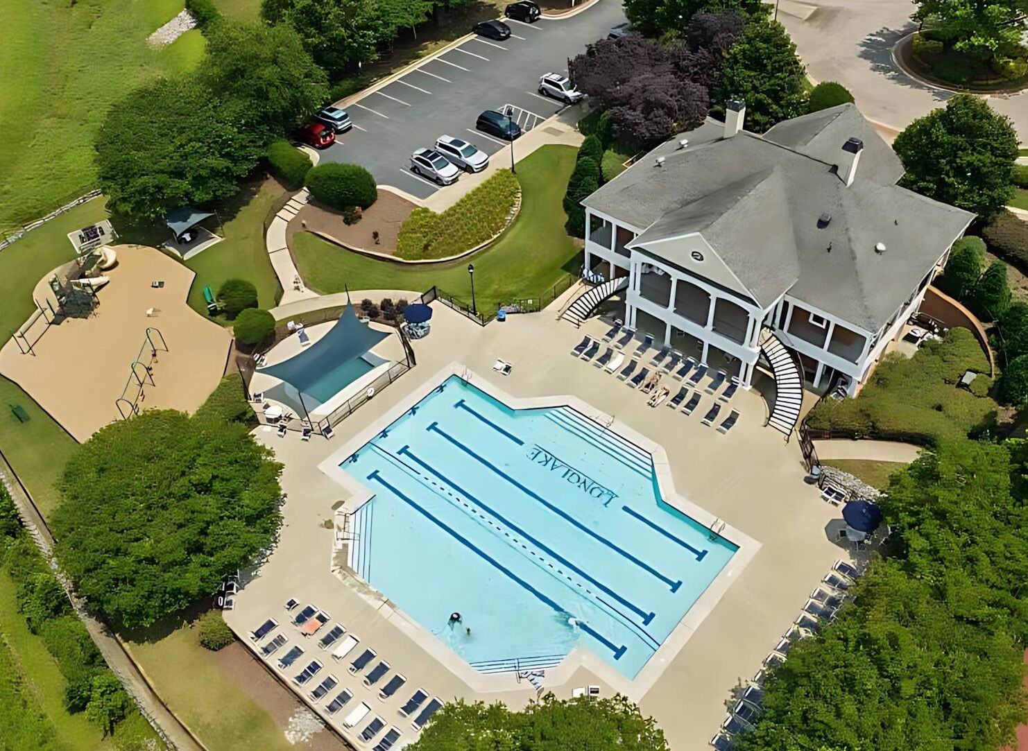 A large swimming pool with multiple lanes, surrounded by lounge chairs and a covered area.