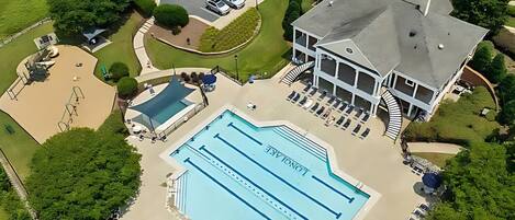 A large swimming pool with multiple lanes, surrounded by lounge chairs and a covered area.