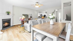 Amplia sala de estar con chimenea, una mesa de comedor y una cocina al fondo.