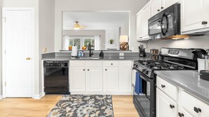 Una cocina moderna con muebles blancos, una estufa negra y un microondas.