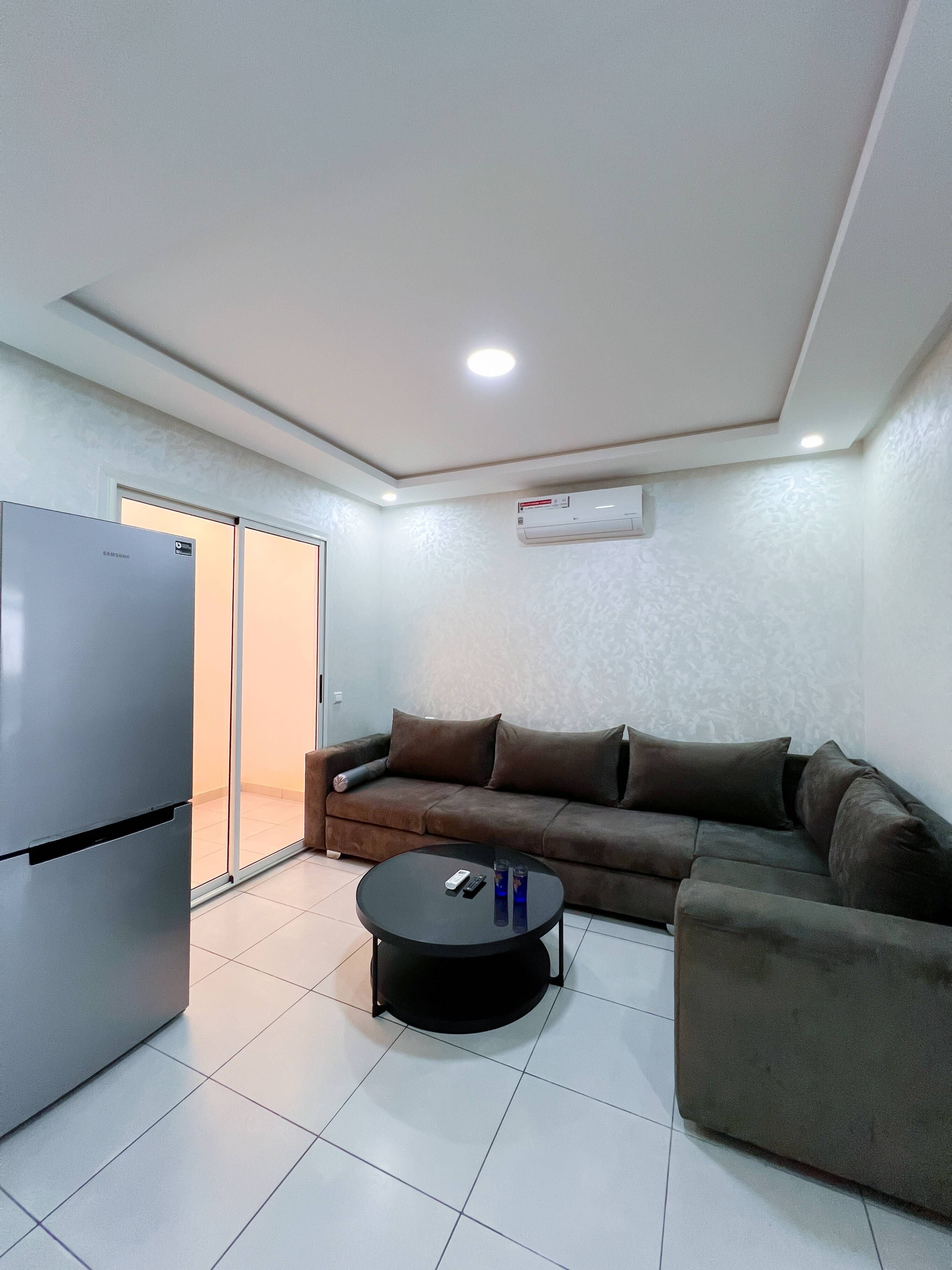 Una sala moderna con un sofá, una mesa de centro y un refrigerador.