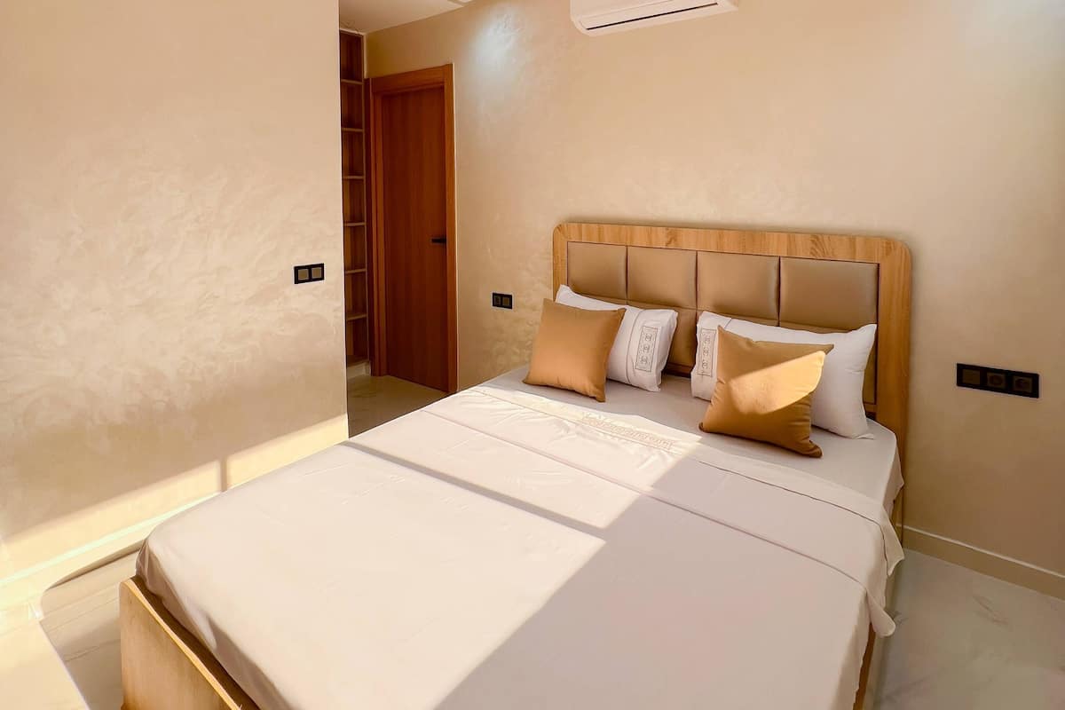 A modern bedroom with a large bed, wooden headboard, and a built-in wardrobe.