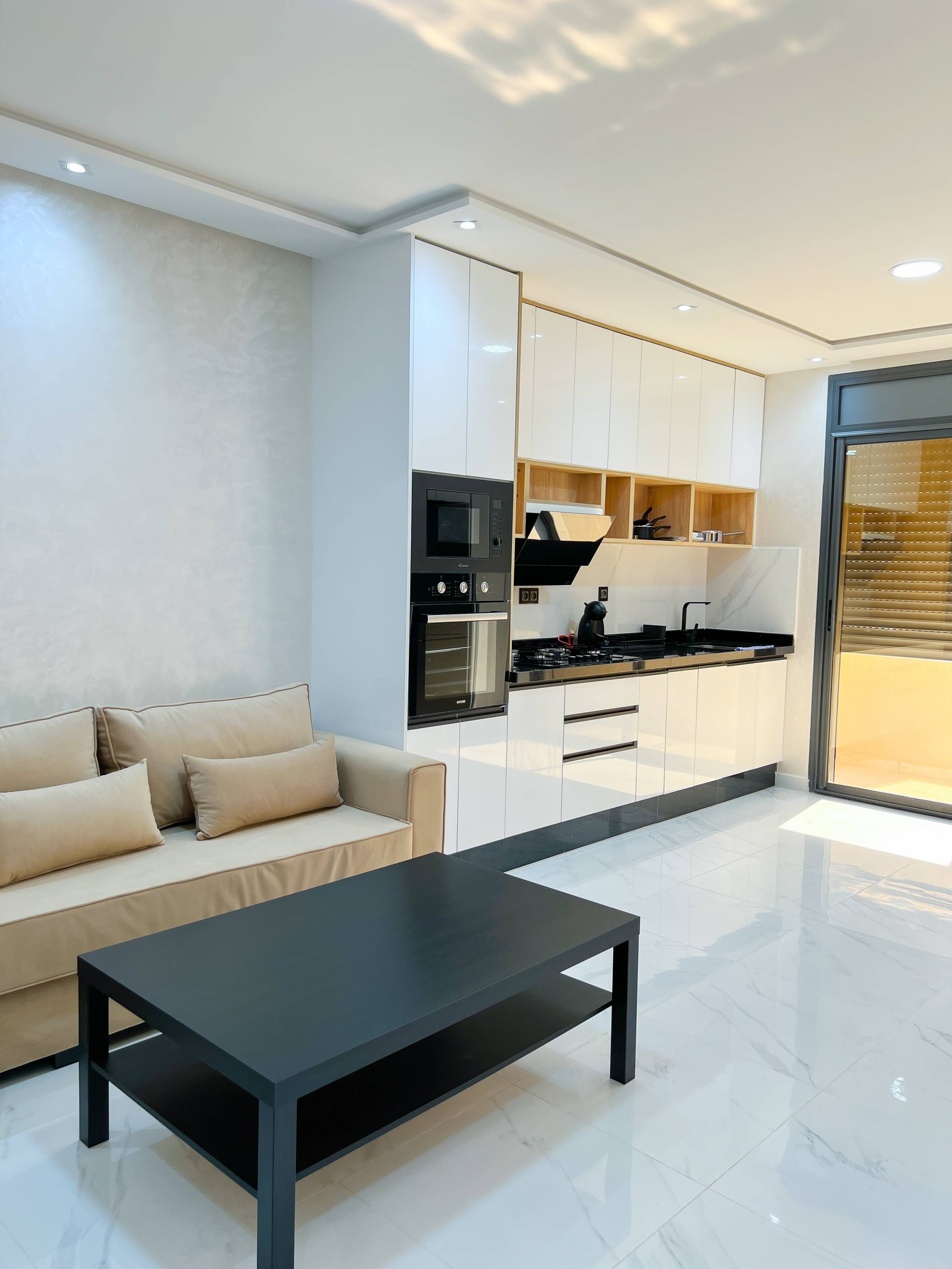 A modern kitchen with white cabinets, a black countertop, and a built-in oven.