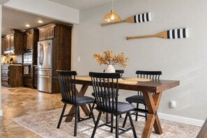 Une cuisine moderne avec des meubles en bois foncé, des appareils en acier inoxydable et un coin repas comprenant une table en bois et des chaises noires.
