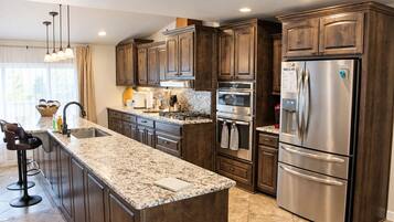 A modern kitchen with dark wood cabinets, stainless steel appliances, and a granite countertop.